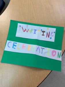 A student-made poster with the words "writing celebration" and colorful balloons.