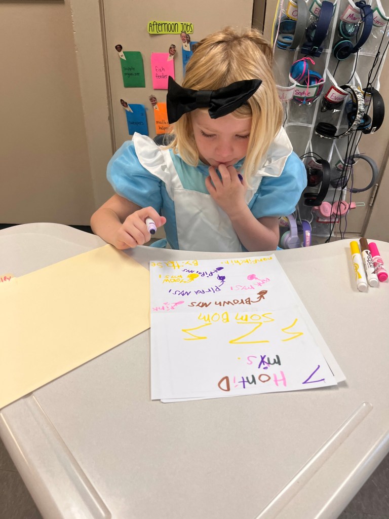 This first grader, clad in her Halloween costume, writes a spooky story called "Seven Haunted Mice."