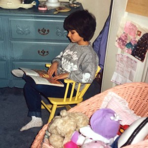 Lauren Castillo sitting in a yellow chair reading a book.